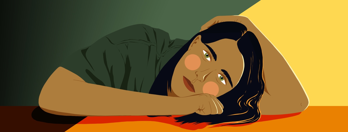 A woman rests her head on her arm, looking exhausted.